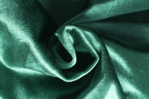 Close-up of emerald green velvet fabric showcasing its luxurious sheen and texture, perfect for design projects.
