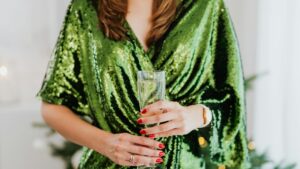 Woman in a sparkling green dress, holding a champagne glass, creating a festive atmosphere.
